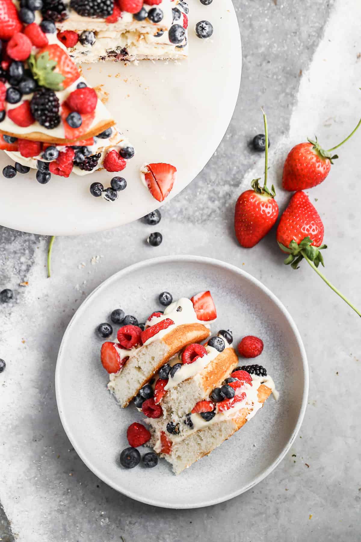 A fresh Berry Cake recipe with one slice cut and served on a plate.