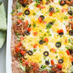 Everyone loves this easy 7-layer bean dip that has layers of flavored refried beans, guacamole, sour cream, salsa, cheese, olives and green onion. | tastesbetterfromscratch.com