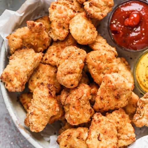 A plate of homemade chicken nuggets cooked in the air fryer, with ketchup and mustard as dipping sauces.