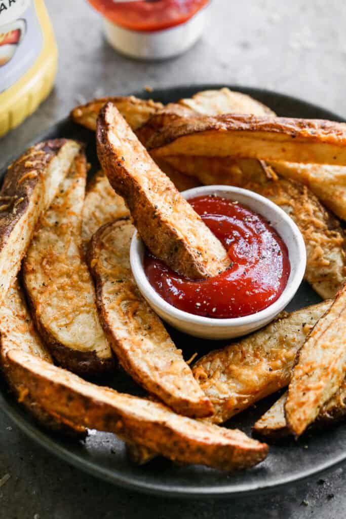 A potato wedge being dipped into ketchup.