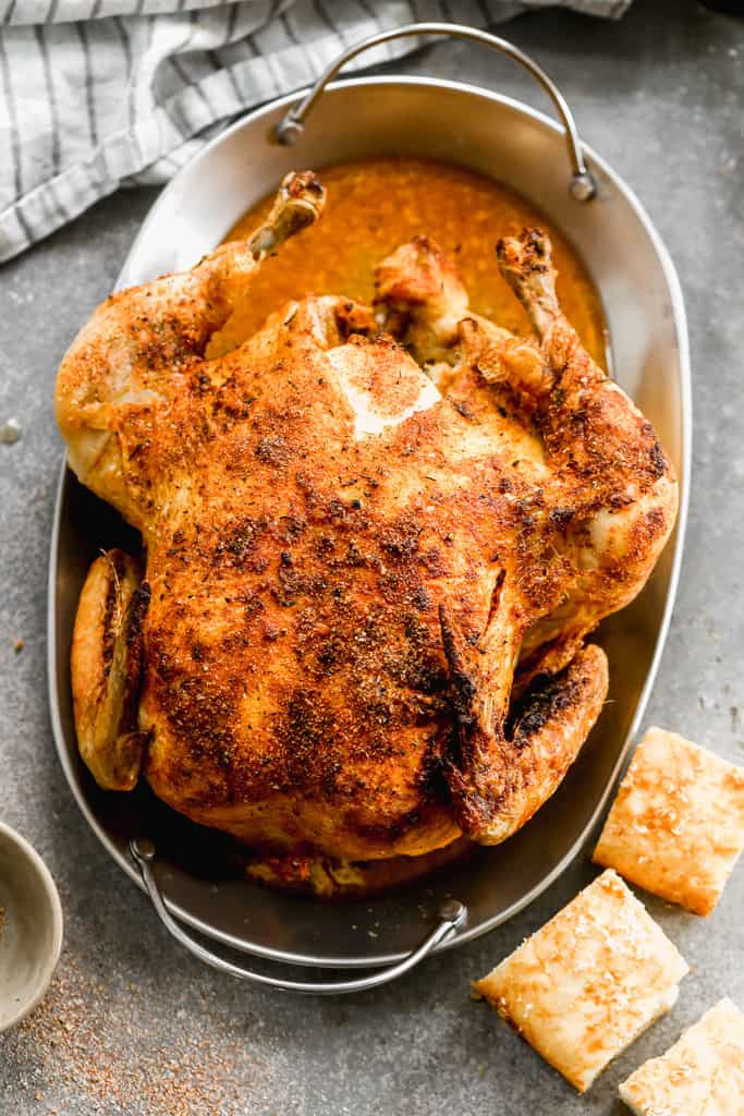 A whole chicken, cooked in the air fryer, served on a platter.