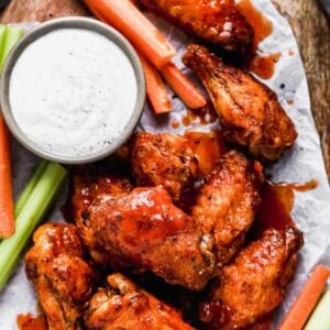 Air Fryer Chicken Wings on a wood board with ranch and veggies.