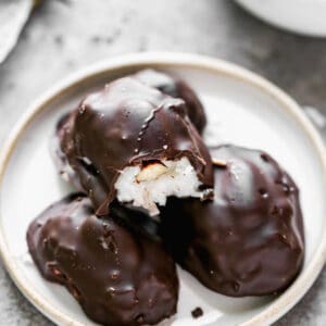 A homemade almond joy candy with a bite out of it, stacked on top of three more.