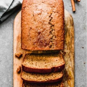 Applesauce bread on a bread board with three slices cut from it.