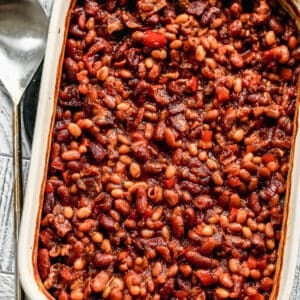 Baked beans in a 9x13 inch baking dish, with a serving spoon on the side.