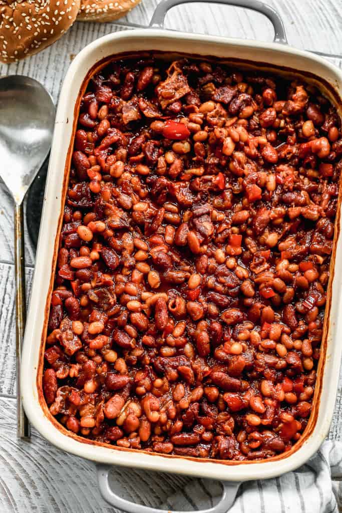 Baked beans in a 9x13 inch baking dish, with a serving spoon on the side.