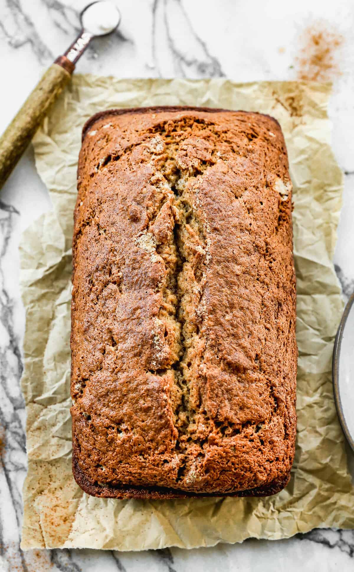 A loaf of easy Banana Bread fresh out of the oven on a sheet of parchment paper.