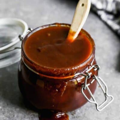 BBQ sauce in a glass jar with a basting brush in it.