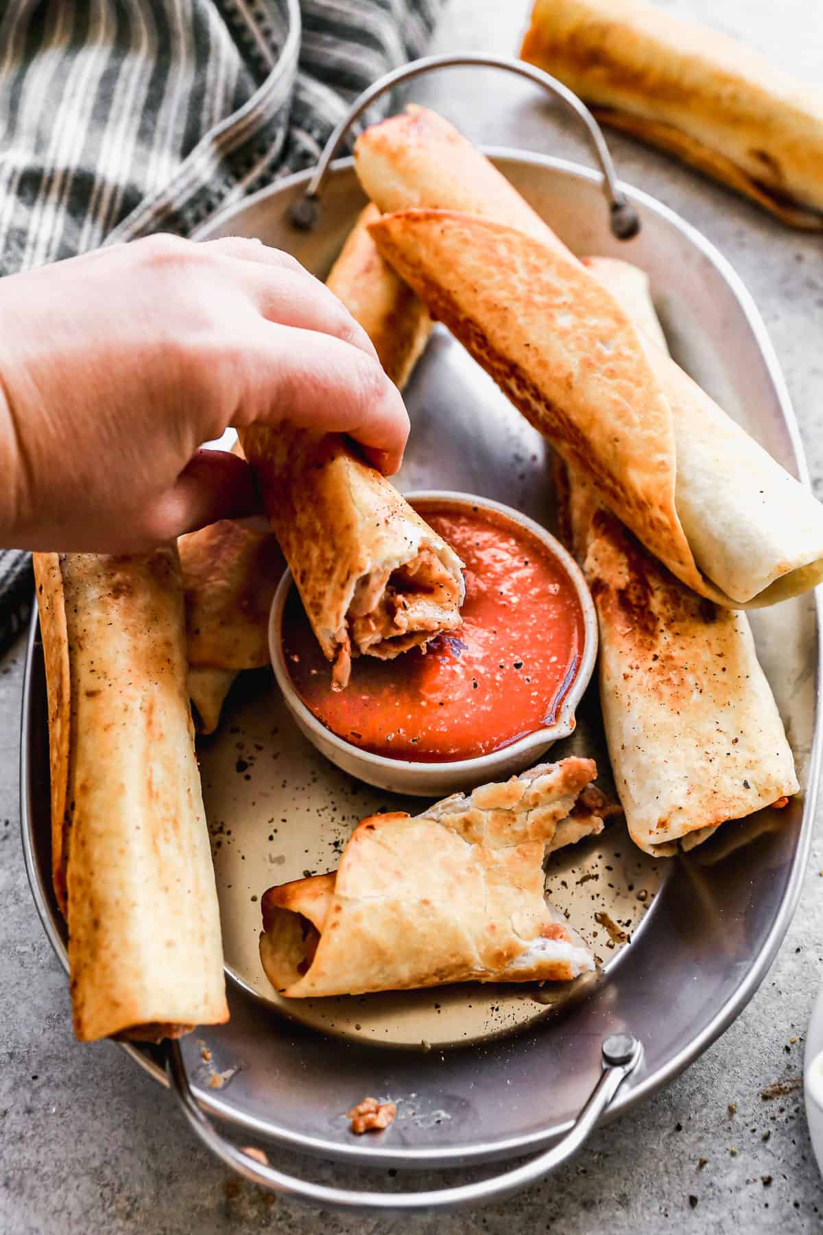 An easy bean and cheese burrito broken in half and being dipped in a little bowl of salsa.