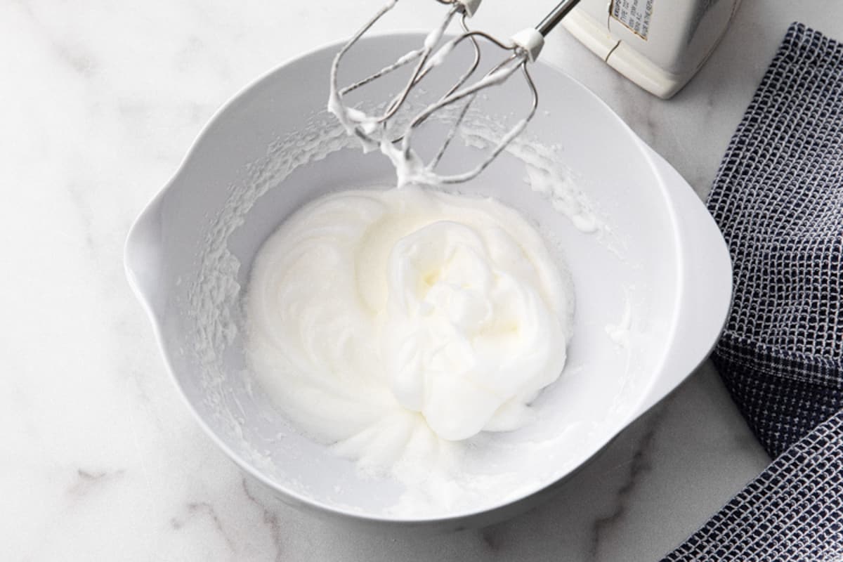 A white mixing bowl with whipped egg whites for fluffy Belgian Waffles.