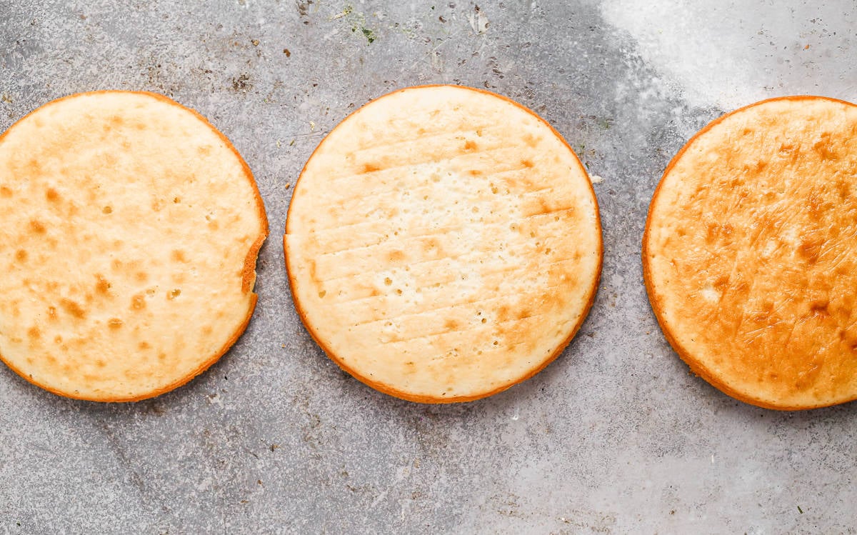 Three thin cake rounds of yellow cake, freshly baked and cooled.