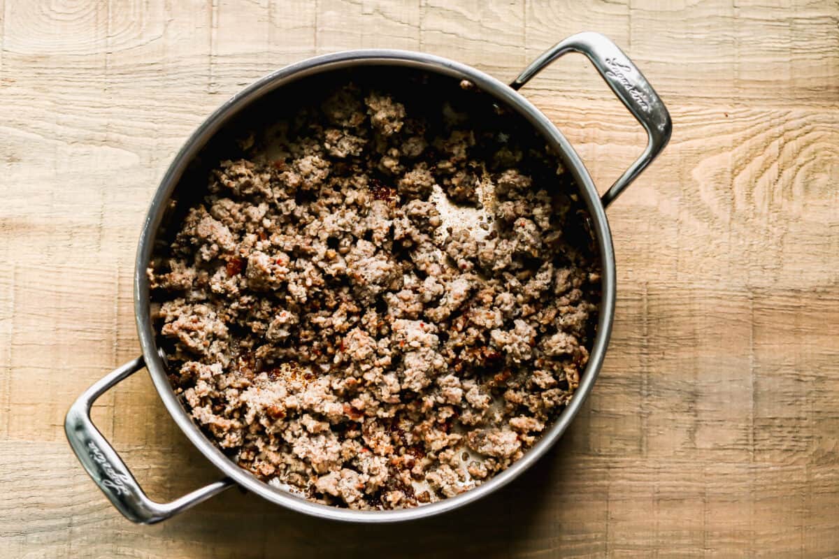 Ground sausage browned and cooked in a large saucepan for a homemade Biscuits and Gravy Casserole recipe.