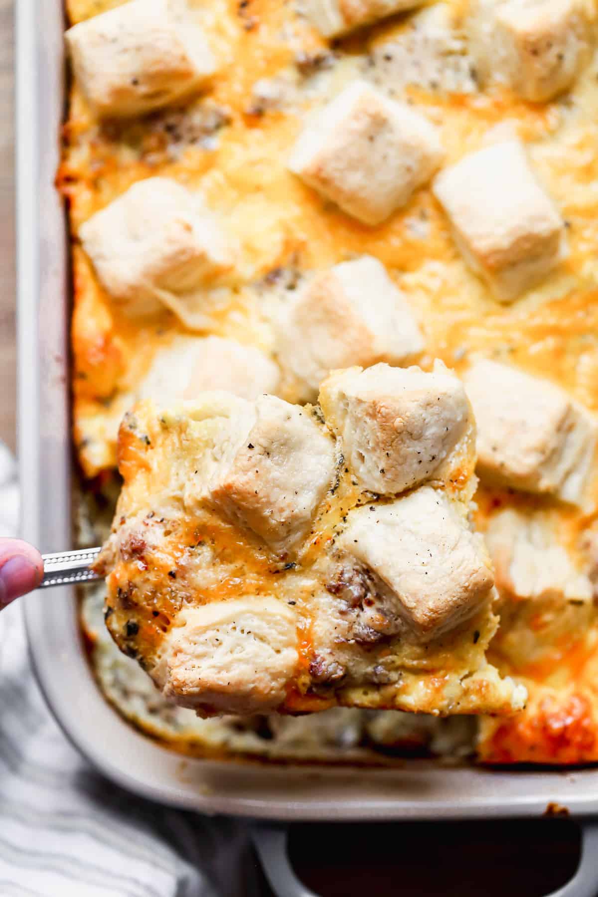 A close up image of a piece of the best Biscuit and Gravy Casserole being lifted out of a baking dish.