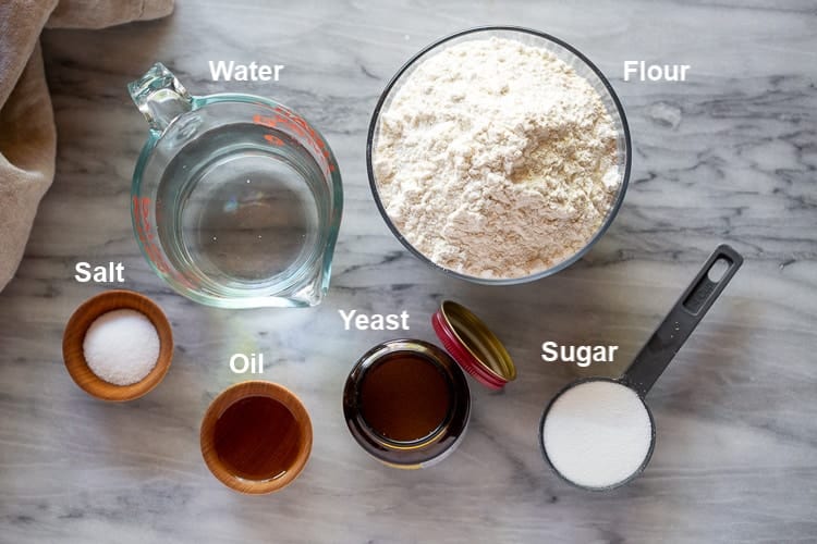 The ingredients needed to make bread including flour, sugar, yeast, water, oil and salt.