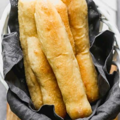 Long thin homemade breadsticks in a basket.