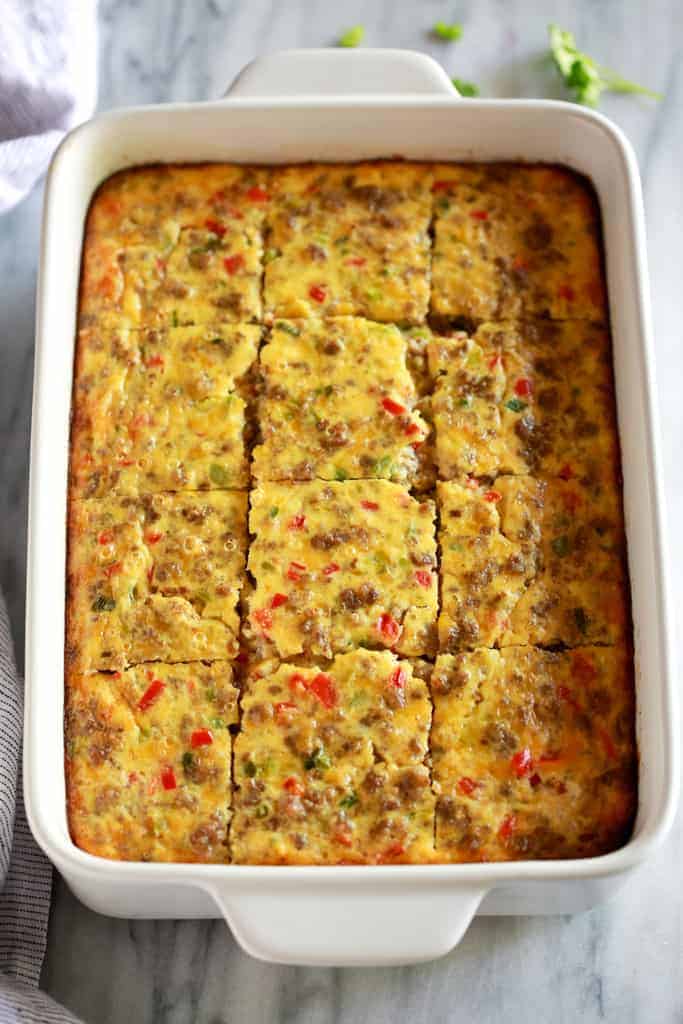 Breakfast casserole baked in a 9x13'' white pan and cut into twelve servings.