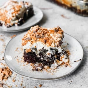 A square of easy Butterfinger Cake on a white plate, ready to enjoy.