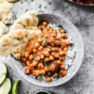 A bowl of easy Chickpea Curry in a bowl on top of rice with naan on the side.