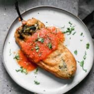 A plate with chile relleno topped with salsa roja.