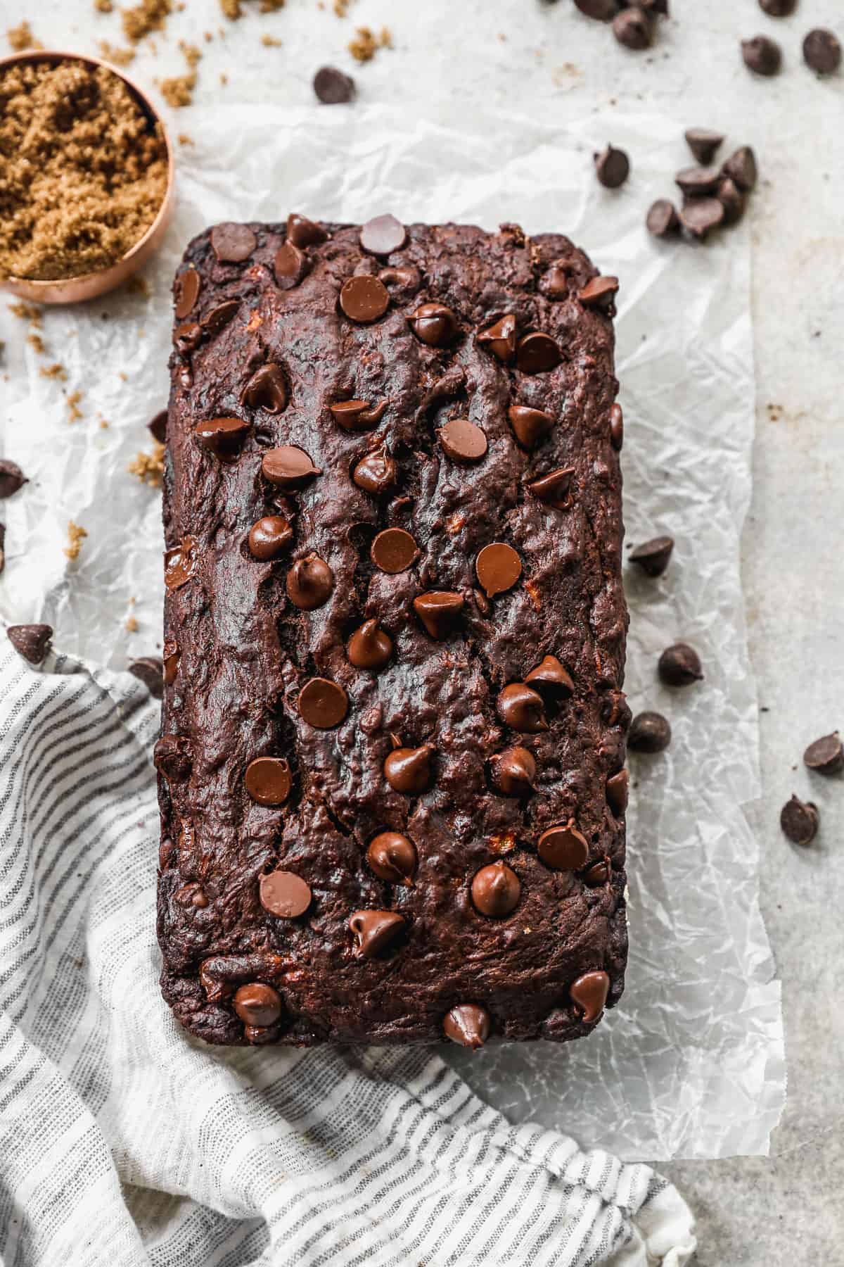 A loaf of Chocolate Banana Bread fresh out of the oven on a piece of parchment paper.