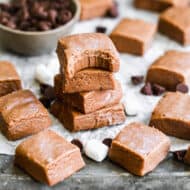 Squares of easy Chocolate Fudge stacked on top of each other, with a bite taken out of the top one.