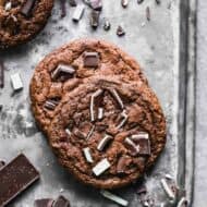 Two baked Chocolate Mint Cookies on a baking tray with andes mints in the background.