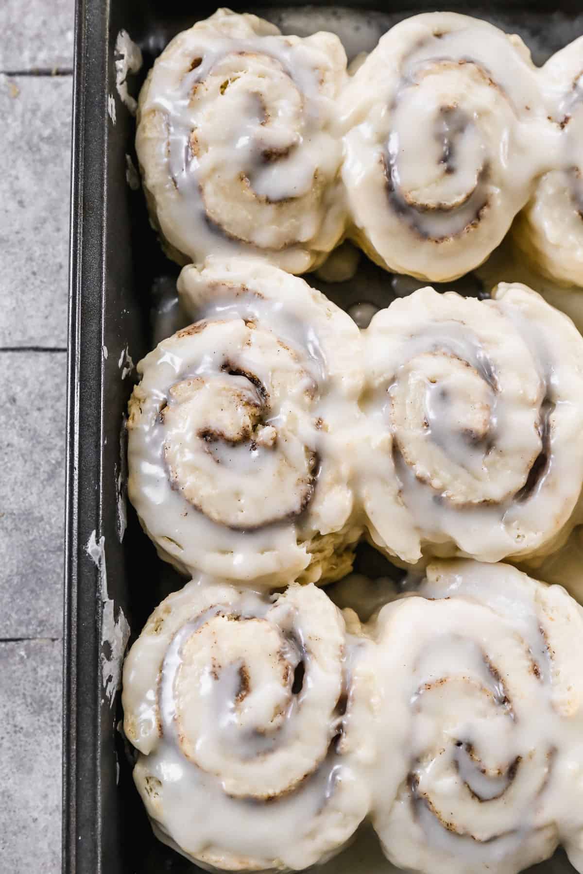 A pan of soft Cinnamon Roll Biscuits with cream cheese frosting on top.