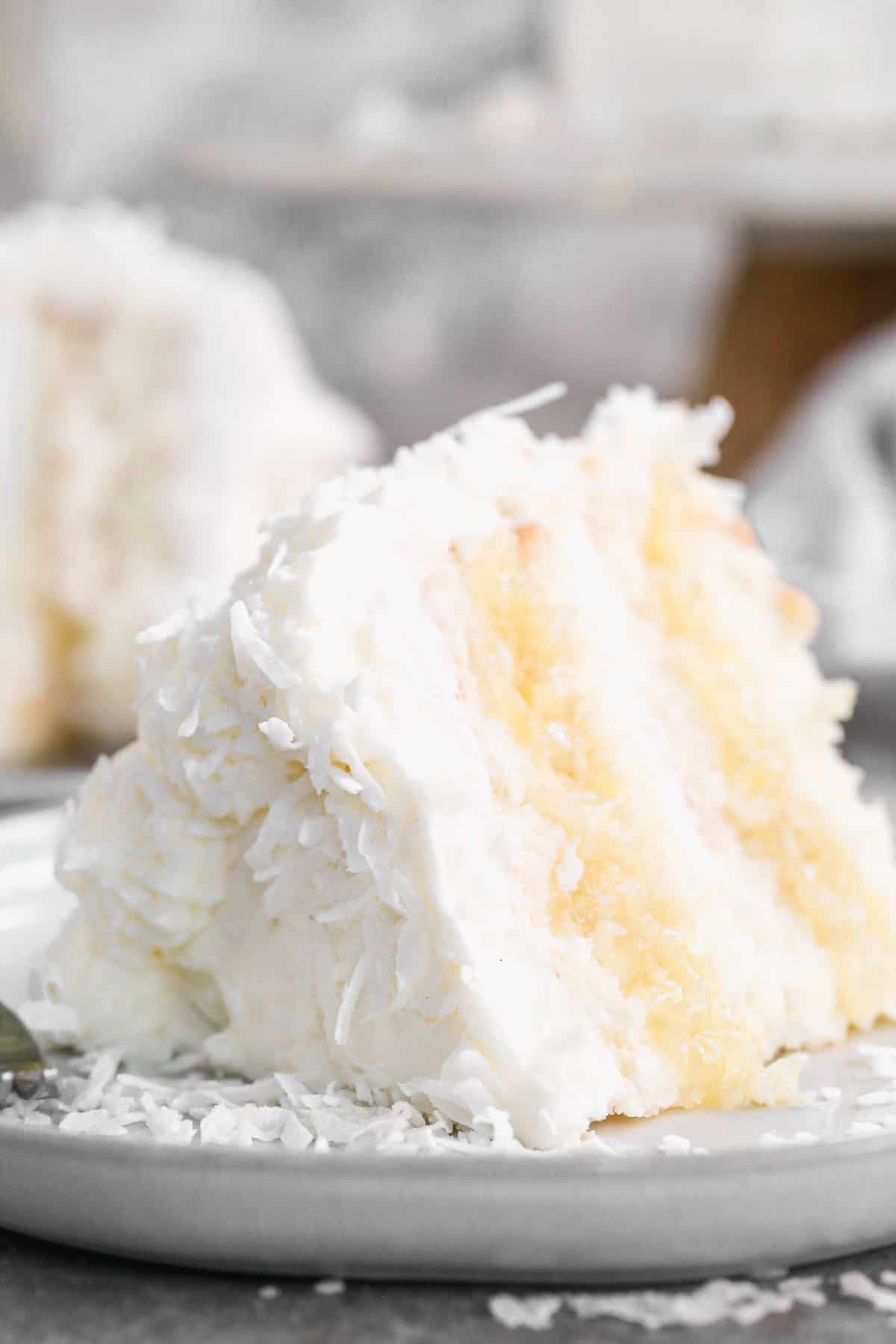 A slice of homemade Coconut Cake with delicious pineapple filling on a plate ready to enjoy.