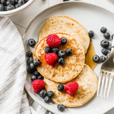 Three Cottage Cheese Pancakes topped with blueberries, raspberries, and pure maple syrup.