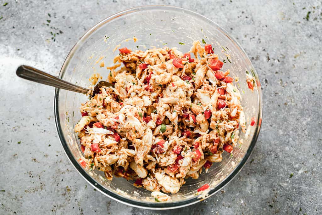 Refrigerated crab cake mixture stirred together in a bowl, ready to form patties.