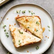 Croque monsieur sandwich cut in half and served on a plate.