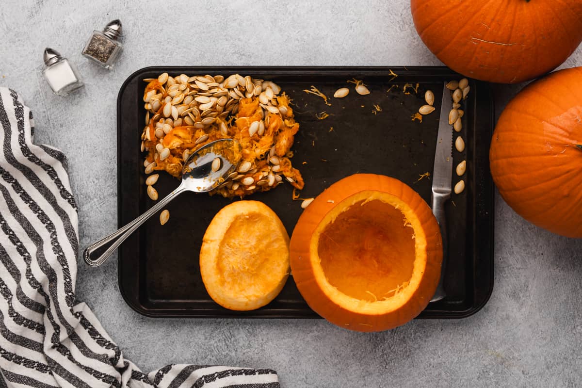 A pie pumpkin on a baking sheet with the seeds scooped out.