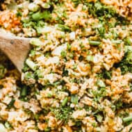 A close up image of a wooden spoon in a pan of an easy dirty rice recipe, ready to serve.