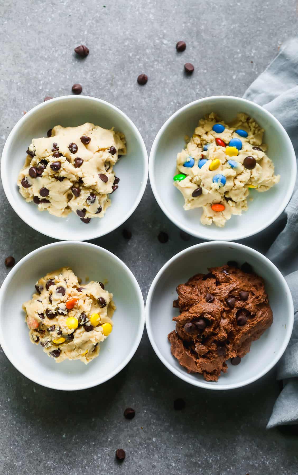 An easy edible cookie dough recipe that is being used to make 4 different cookie dough flavors, each in their own bowl: chocolate chip, peanut butter, m&m, and double chocolate.