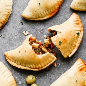 Baked empanadas with the one in the center torn in half.