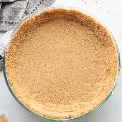 A homemade graham cracker pie crust in a clear glass pie dish.