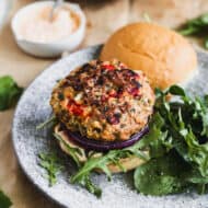 A Greek Turkey Burger on a plate with a homemade feta aioli, charred red onion, and fresh arugula.