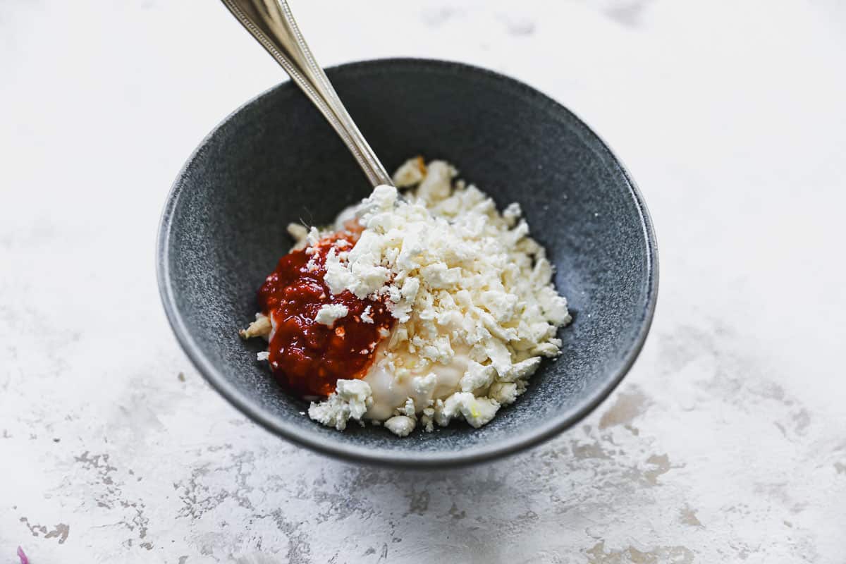 Feta cheese, mayonnaise, greek yogurt, garlic, harissa paste, and salt and pepper in a bowl to make a homemade feta aioli. 