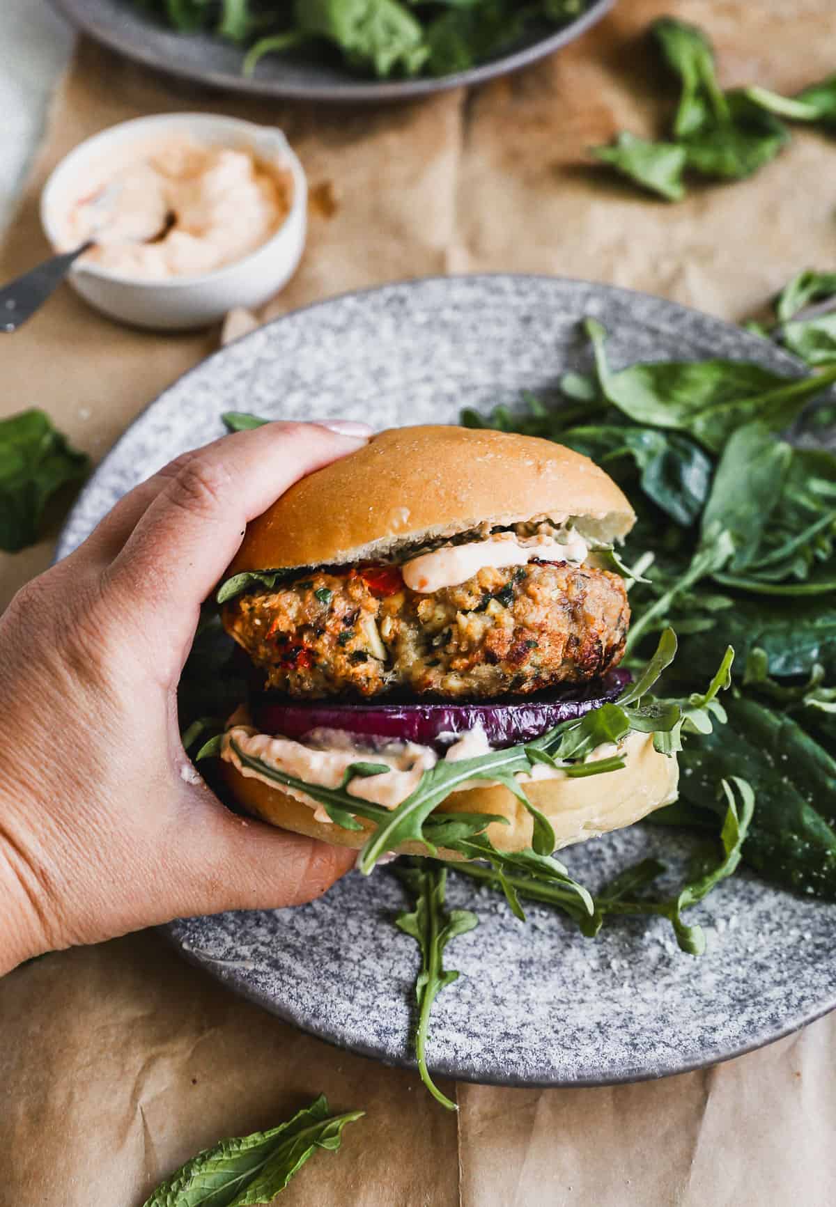 Someone holding a homemade Greek Burger with an easy feta aioli, ready to enjoy.