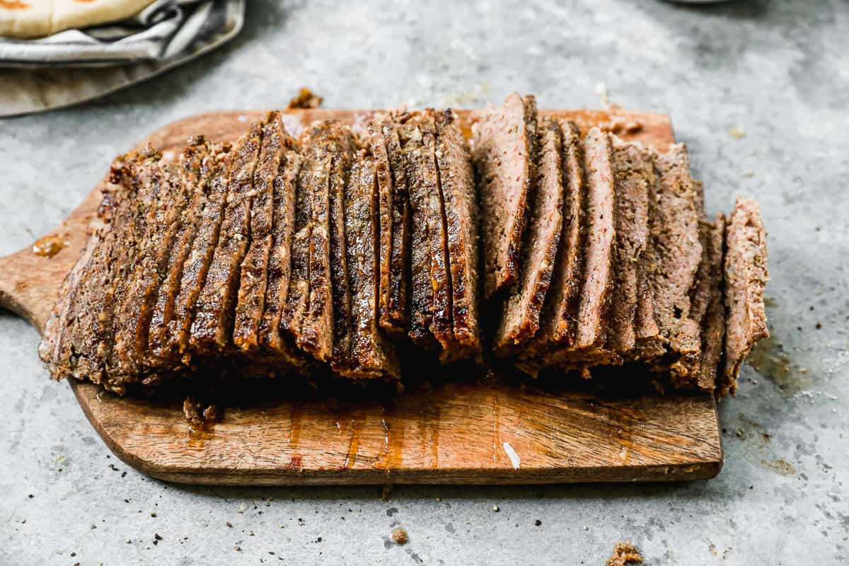 Gyro meat sliced into thin slices on a cutting board.