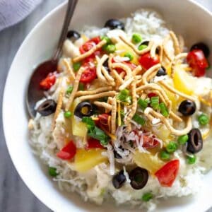 Hawaiian haystacks served over white rice, in a bowl with a spoon.