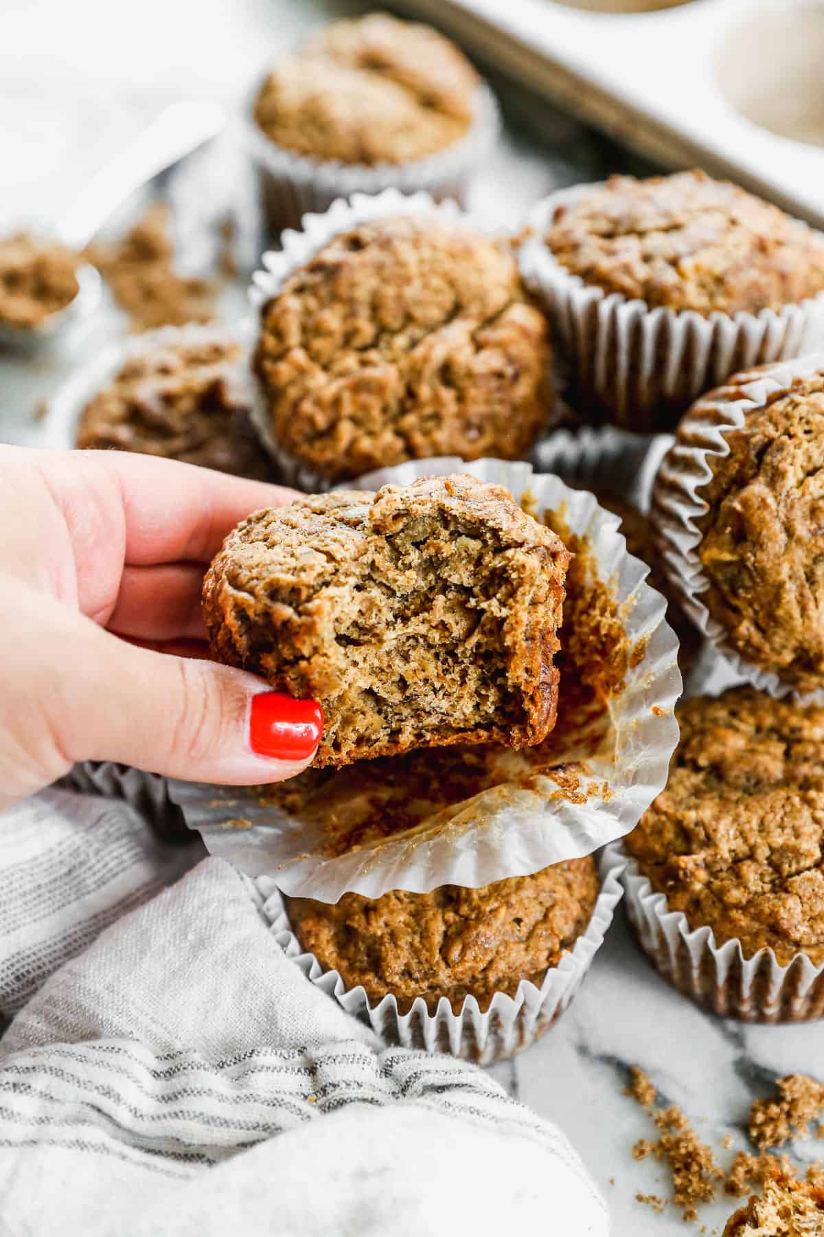 A healthy banana bread muffin with a bite taken out, showing how fluffy and soft it is.