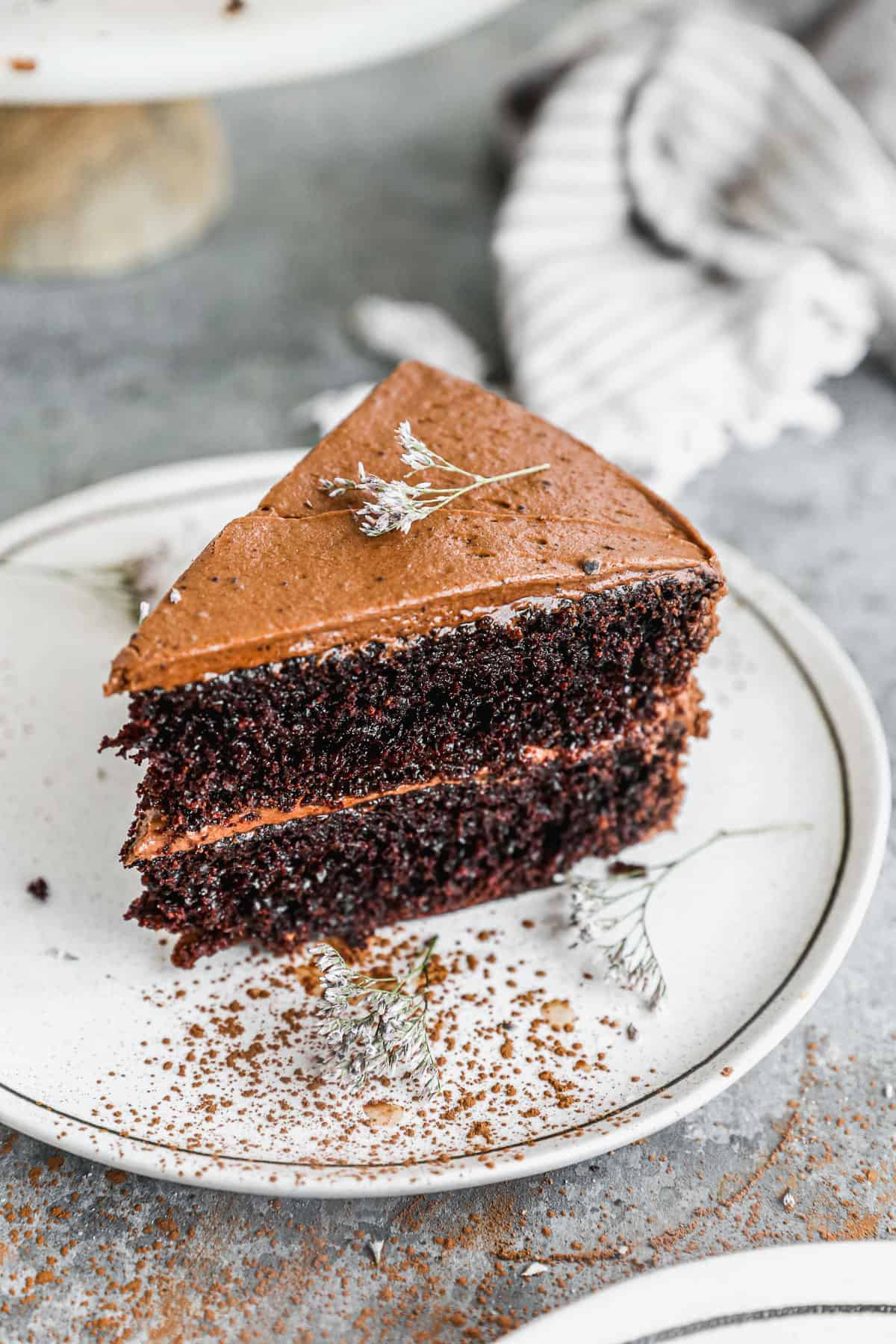 A slice of a two layer cake sitting upright on a white plate.