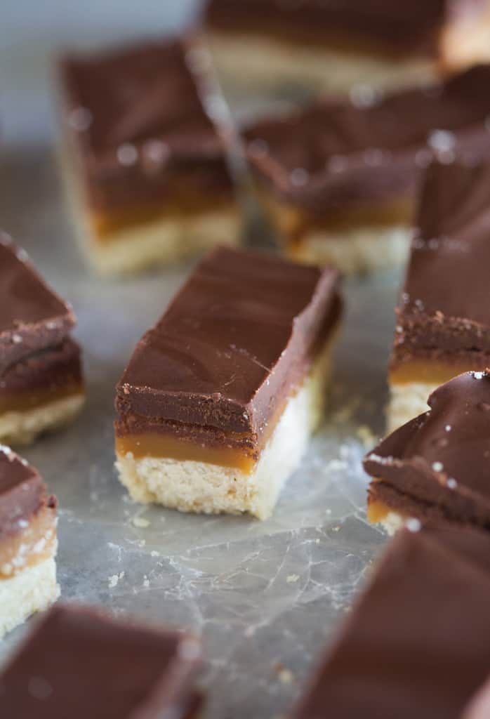 A homemade twix cookie bar with a shortbread crust, middle layer of caramel and topped with chocolate.