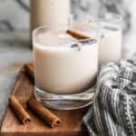 Horchata in a glass of ice topped with a cinnamon stick.