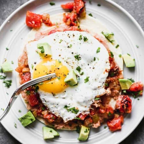 Homemade huevos rancheros on a plate with a fork.