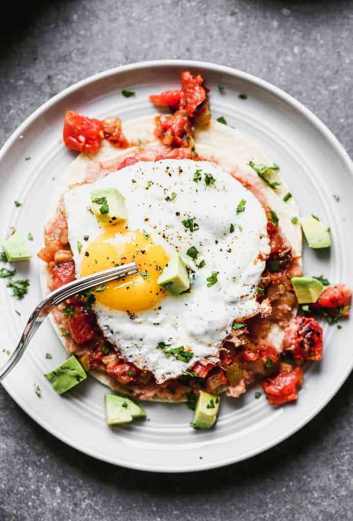 Homemade huevos rancheros on a plate with a fork.