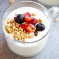 Instant pot yogurt served in a cup with berries and granola on top.