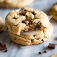 Two Jumbo Chocolate Chip Cookies stacked on top of each other with a bite taken out of the top cookie.