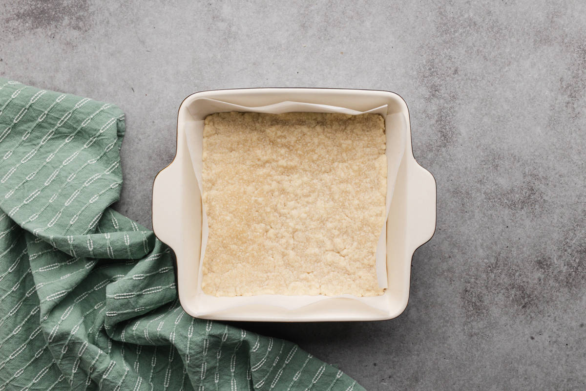 A shortbread crust freshly baked and ready to be topped with lemon filling for an old fashioned lemon squares recipe.